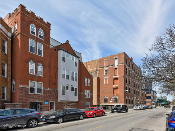 Front view of a multi-story brick building with a mix of arched and rectangular windows.