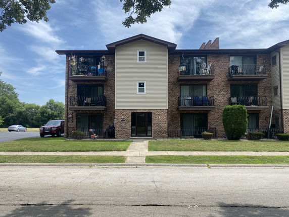 Front view of a three-story apartment building with balconies.