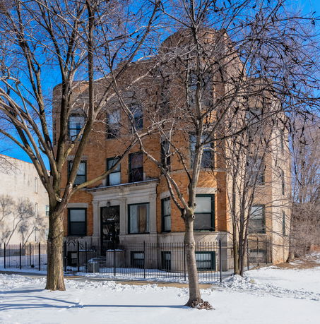 Front view of a multi-story brick building with snow-covered ground and bare trees.
