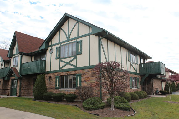 Front view of a two-story house with decorative green trim and a brick facade.