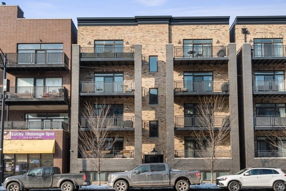 Front view of a multi-story building with balconies and brick exterior.