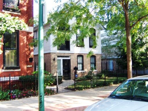 Front view of a two-story house with a small front yard and fencing.