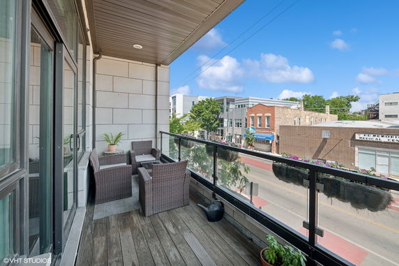 Balcony with chairs overlooking a street and buildings in an urban area.