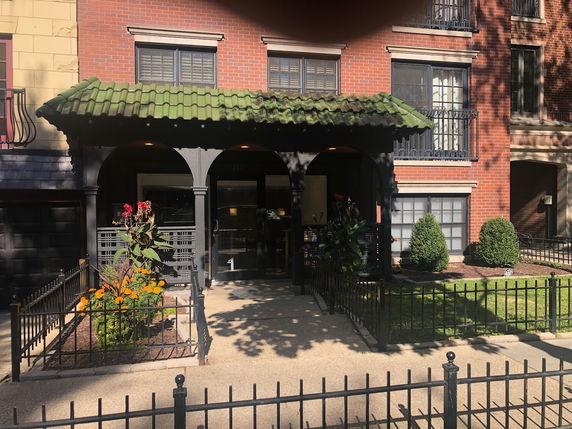 Front view of a multi-story building with a green tile roof entrance.
