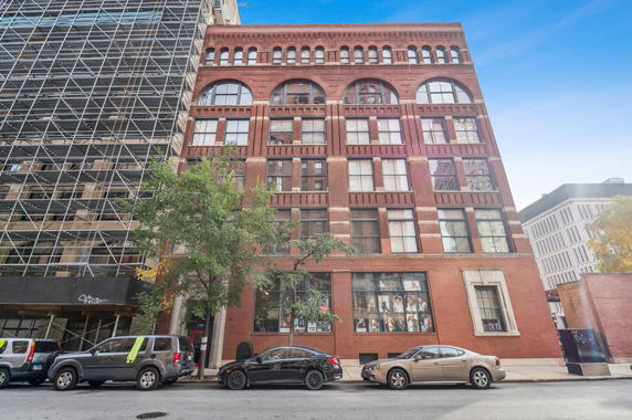 Front view of a multi-story brick building with large arched windows.