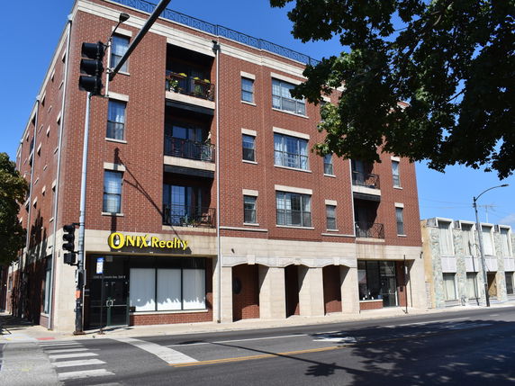 Front view of a four-story commercial and residential building with a real estate office on the ground floor.