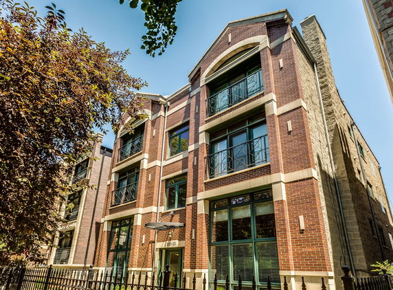 Front view of a multi-story brick building with large windows and balconies.