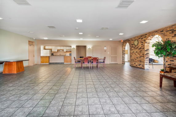 Indoor area with tiled floor, dining table, chairs, and brick archway.