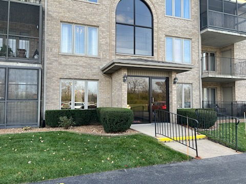Front view of a multi-story apartment building with large windows and a central entrance.