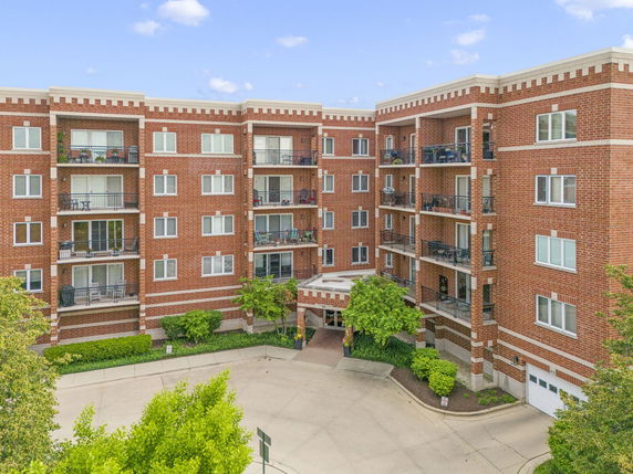 Front view of a multi-story brick apartment building with balconies.