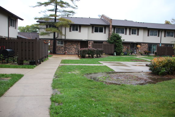 Front view of a two-story building with brick facade and fenced patio areas.