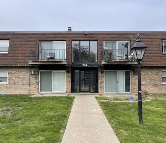Front view of a two-story apartment building with balconies and a central entrance.