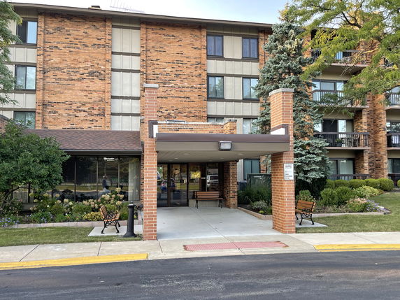 Front view of a multi-story brick building with a covered entrance.