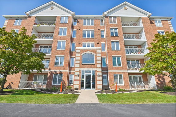 Front view of a multi-story brick apartment building with balconies.