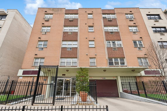 Front view of a multi-story brick building with gated entrance.