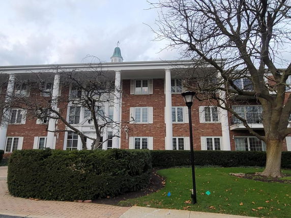 Front view of a three-story building with brick facade and white columns.