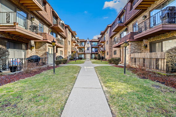 Front view of apartment buildings with multiple balconies and brick facade.