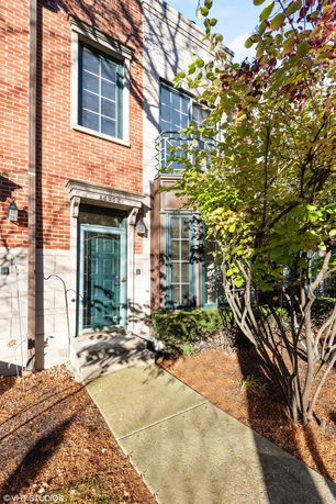 Front view of a brick facade townhouse with a green door and large windows.