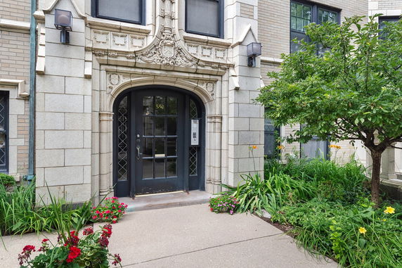 Front view of a building with ornate stone entrance and greenery.