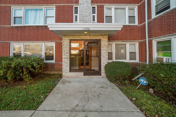 Front view of a brick multi-story residential building entrance with a glass door.