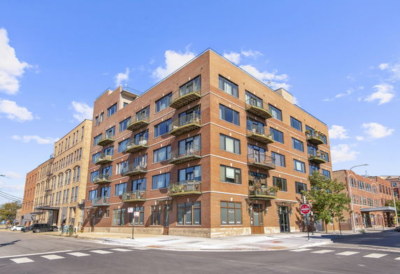 Front view of a multi-story brick apartment building with balconies.