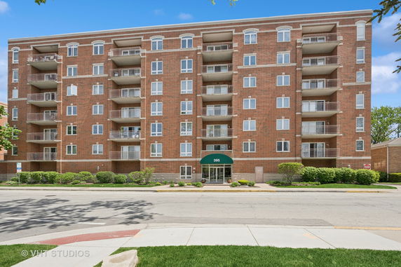 Front view of a six-story brick apartment building with balconies.