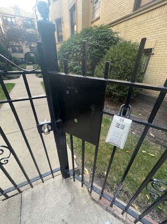 Front view of a building with a security gate featuring a keypad entry system.