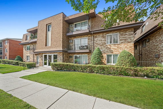 Front view of a multi-story brick apartment building with balconies.