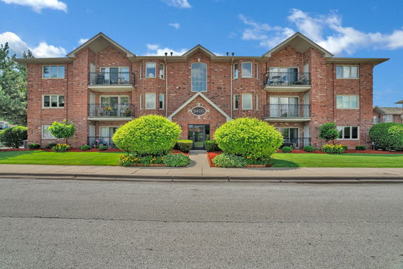 Front view of a three-story brick building with balconies.