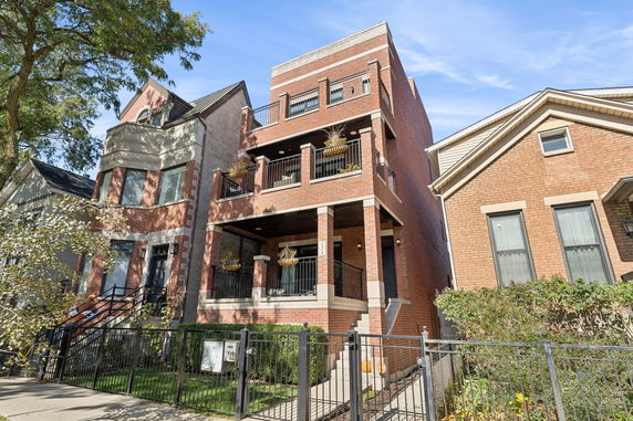 Front view of a three-story brick house with balconies.