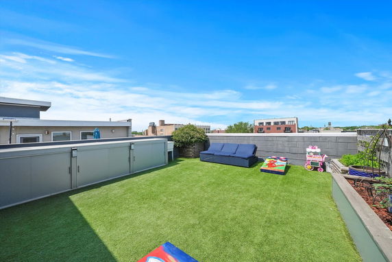 Open rooftop area with green flooring, potted plants, and outdoor seating.