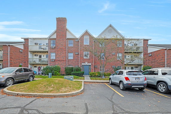 Front view of a three-story multi-unit brick building with balconies.