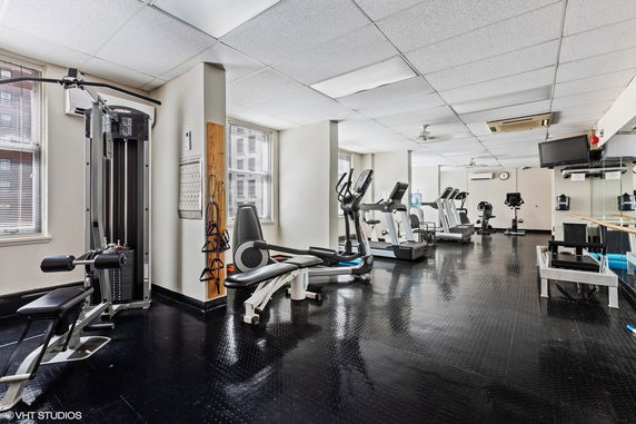 Interior view of a gym with exercise equipment and large windows.