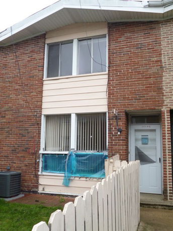 Front view of a two-story brick house with a small fenced entryway.