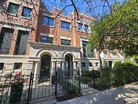 Front view of a brick residential building with arched entrances and decorative columns.