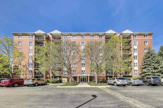 Front view of a multi-story residential building with a parking area in front.