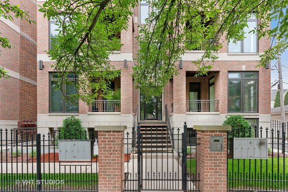 Front view of a multi-story brick building with stairway entrance and balconies.