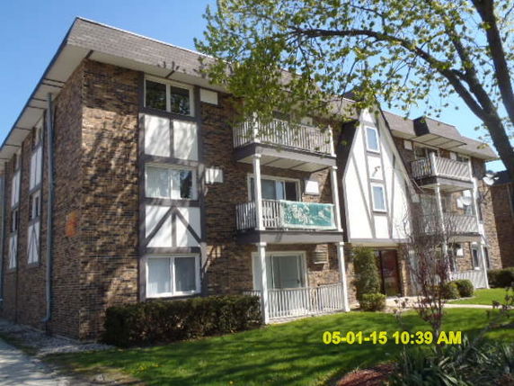 Front view of a three-story brick apartment building with balconies.