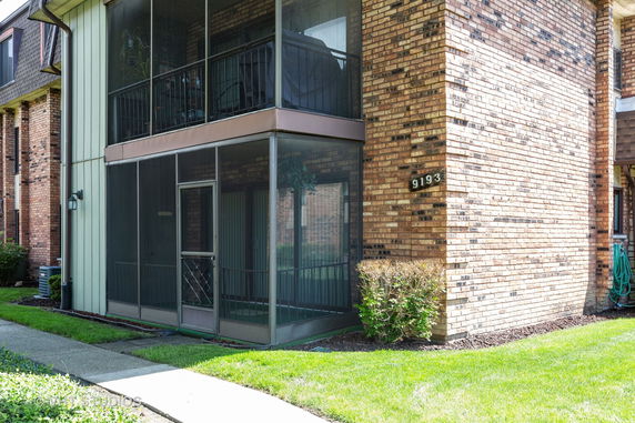 Front view of a multi-story brick building with an enclosed balcony.