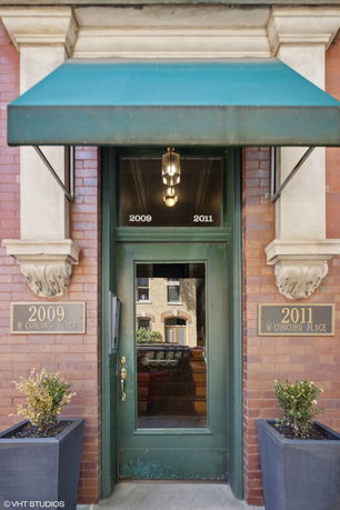 Front view of a building entrance with a green awning and two plaques indicating address numbers.