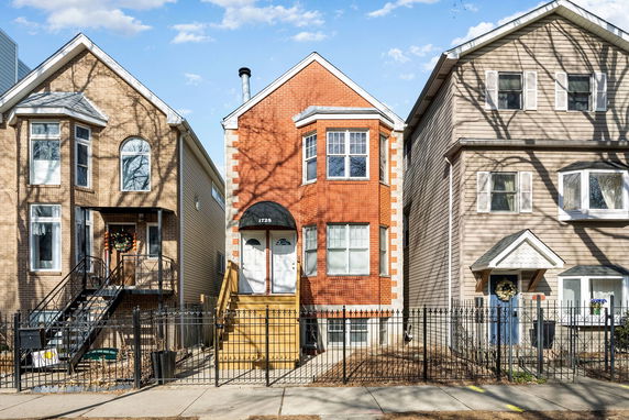 Front view of a row of three-story houses with brick and siding exteriors.