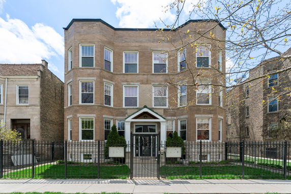 Front view of a multi-story brick building with a central entrance and multiple windows.