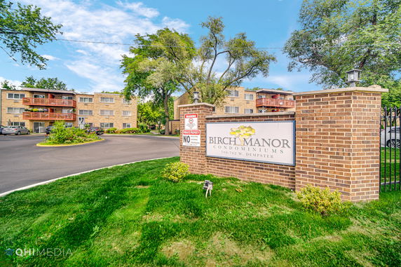 Front view of Birch Manor condominiums with a brick sign at the entrance.