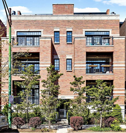 Front view of a three-story brick apartment building with balconies.