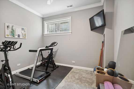 Room with exercise equipment including a treadmill and stationary bike.