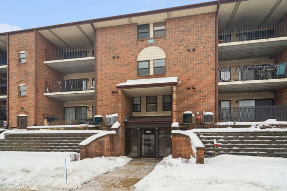 Front view of a multi-story brick building with balconies and a central entrance.
