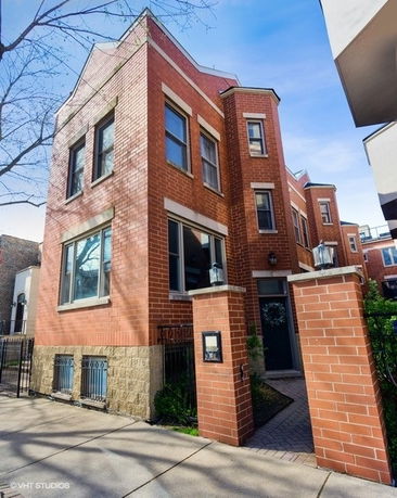 Front view of a three-story brick house with multiple windows and an entrance gate.