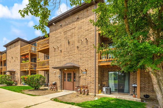 Front view of a multi-story brick apartment building with balconies.