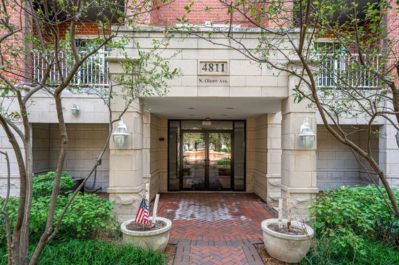 Front view of a building entrance with brick pathway and greenery.