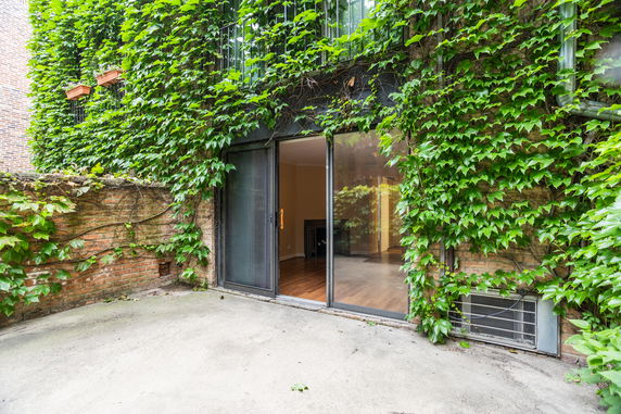 Exterior view of a house with ivy-covered walls and sliding glass doors leading inside.
